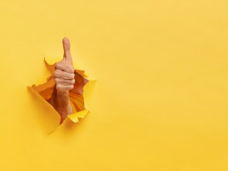 A "thumbs up" bursting through a yellow background