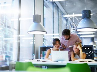 Group of three learners around a laptop